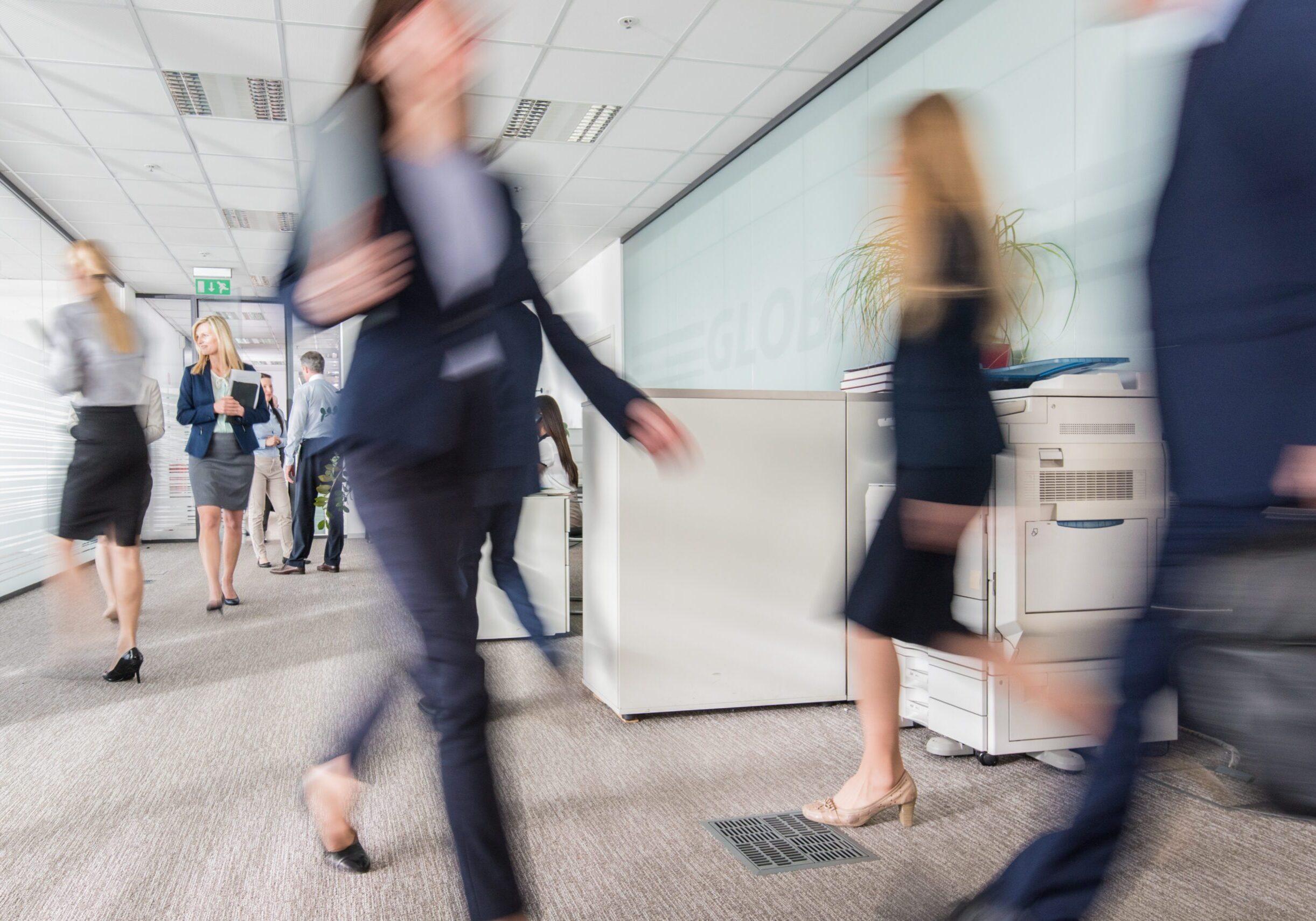 Blurred motion of businesswoman holding document and walking in office building.